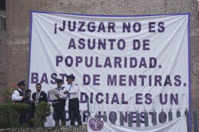 Security personnel stand at a federal court as unionized federal court workers gather outside to strike over reforms that would make all judges stand for election in Mexico City, Monday, Aug. 19, 2024. The sign reads in Spanish "Judging is not a popularity issue. Stop the lies. The judiciary is an honest power." (AP Photo/Fernando Llano)